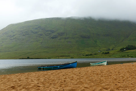 A pair of boats on the red sand in the rain at Lough Nafooey in County Galway. Lough Nafooey is a rectangular shaped glacial lake on the border of County Mayo and County Galway.