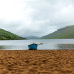 A single blue boat sits on sand in the rain at Lough Nafooey in County Galway. Lough Nafooey is a rectangular shaped glacial lake on the border of County Mayo and County Galway.