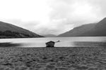 A single boat sits on sand in the rain at Lough Nafooey in County Galway. Lough Nafooey is a rectangular shaped glacial lake on the border of County Mayo and County Galway.
