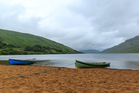 A pair of boats on the red sand in the rain at Lough Nafooey in County Galway. Looking towards the Mayo border. Lough Nafooey is a rectangular shaped glacial lake on the border of County Mayo and County Galway.