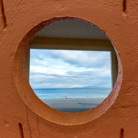 A view through a circular window looking out though a rectangular doorway out to the Atlantic Ocean from a shelter on Salthill Prom in County Galway. 