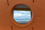 A view through a circular window looking out though a rectangular doorway out to the Atlantic Ocean from a shelter on Salthill Prom in County Galway. 