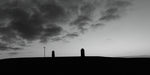 The Lia Fáil and the memorial headstone on the Hill of Tara at sunrise in black and white.
